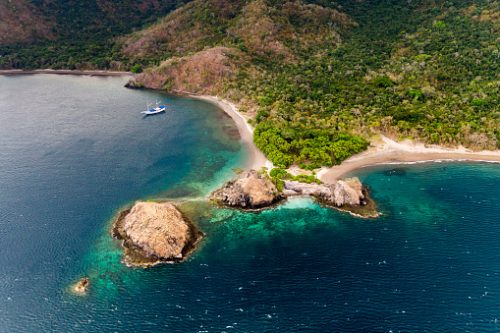 Aerial view of a saiboat parked by secluded beach in Komodo National Park.